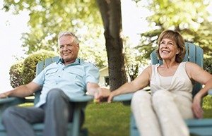 mature couple outdoors in chairs holding hands